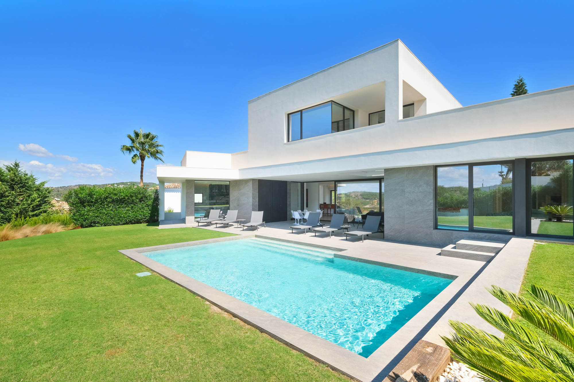 Modern villa with green garden, pool and sun loungers in Sotogrande
